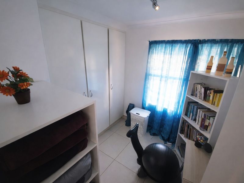 A compact bedroom featuring tiled flooring and white built-in cupboards, offering functional storage space.