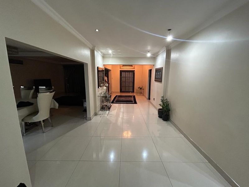 A bright and spacious entrance hall featuring polished tiled flooring, recessed downlighting, and a coved ceiling, leading into the main living areas.