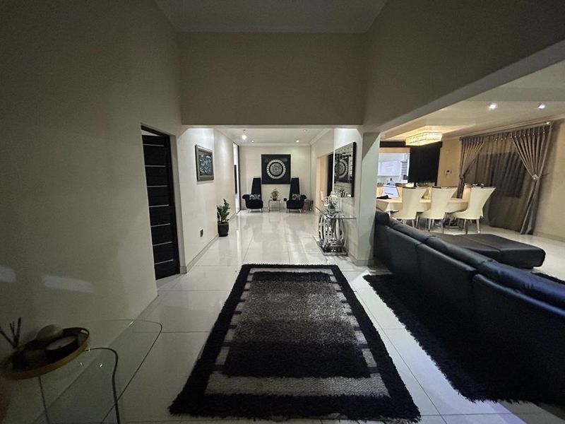 Spacious open-plan living area featuring large format floor tiles, high ceilings, and recessed lighting, seamlessly connecting the lounge and dining spaces.