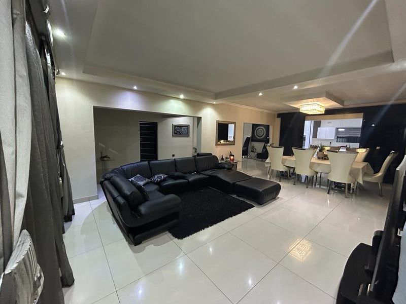Spacious open-plan living and dining area featuring polished tiled flooring, recessed ceiling lighting, and a modern coffered ceiling design.