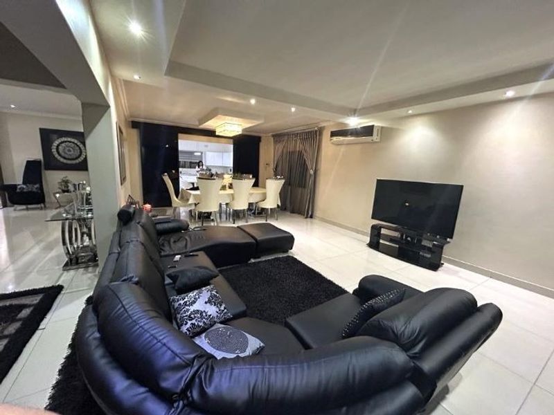 Spacious open-plan living and dining area featuring modern tiled flooring, recessed bulkhead ceiling lighting, and a wall-mounted air conditioning unit.
