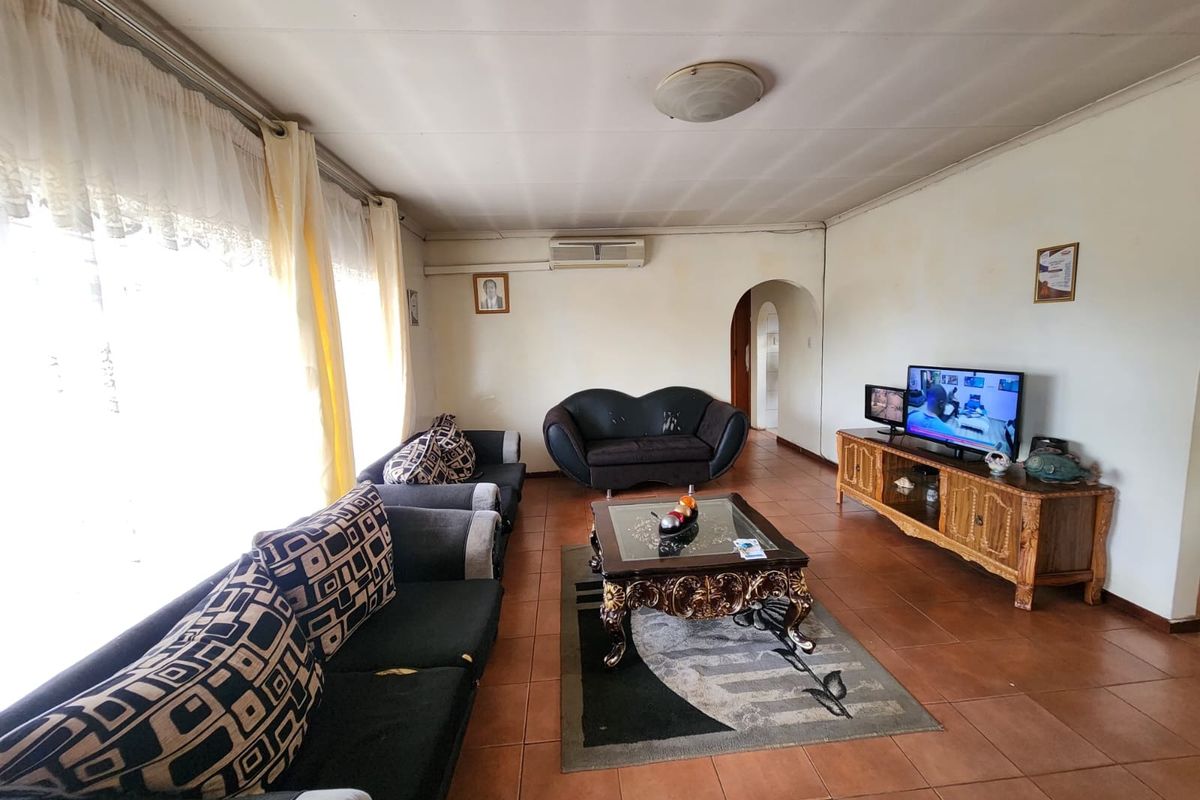 A spacious living room featuring tiled flooring, an air conditioning unit, and a classic archway leading to the rest of the home.