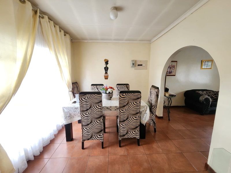 Dining room featuring tiled flooring and a classic arched entryway leading to an adjacent living space.