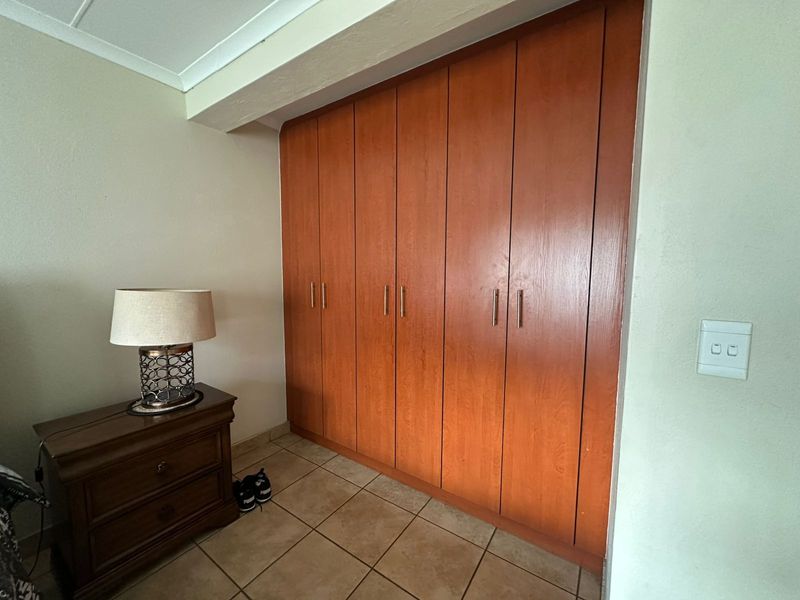 A bedroom featuring floor-to-ceiling built-in wooden cupboards and tiled flooring, providing ample storage space.