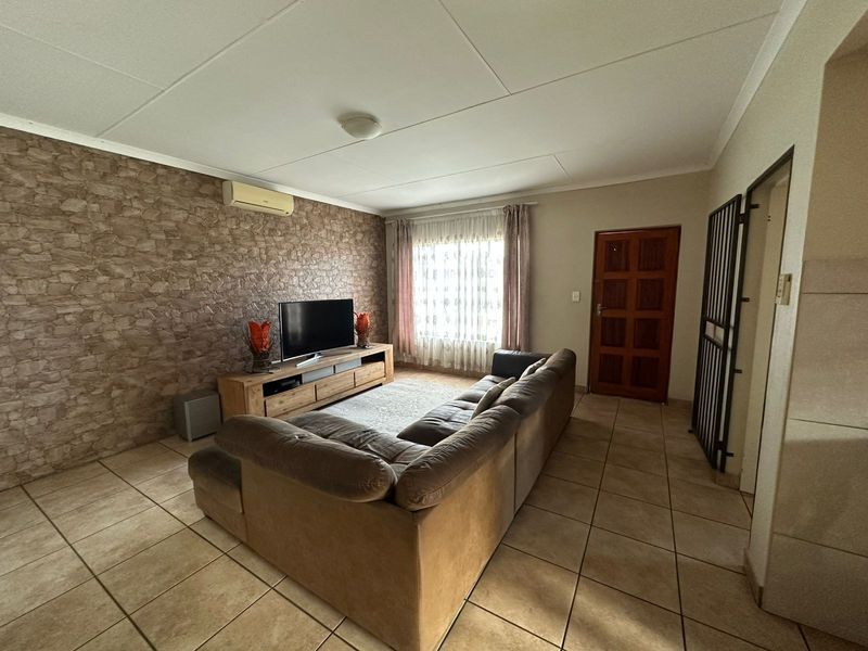 A comfortable living room featuring tiled flooring, a textured feature wall, and a wall-mounted air conditioning unit.