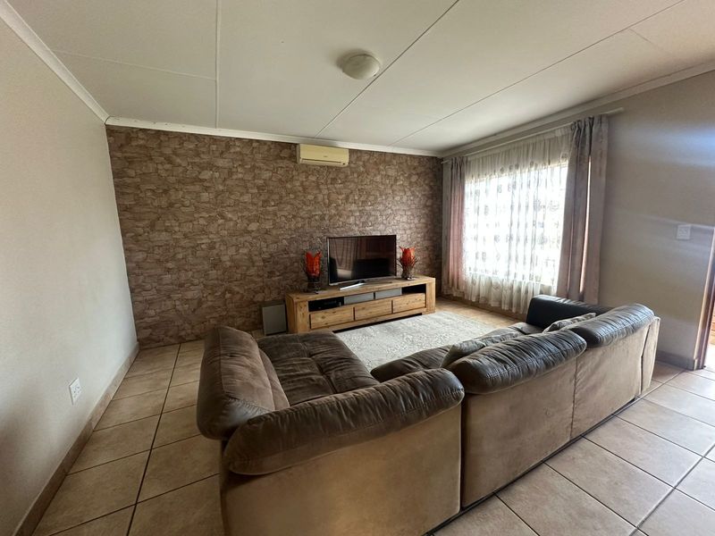 A living room featuring tiled flooring, a textured feature wall, and a wall-mounted split-system air conditioner.