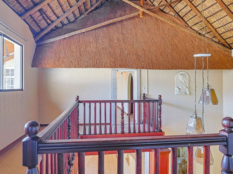 Spacious landing area featuring a high vaulted thatched ceiling with exposed timber trusses and a traditional wooden balustrade overlooking the lower level.
