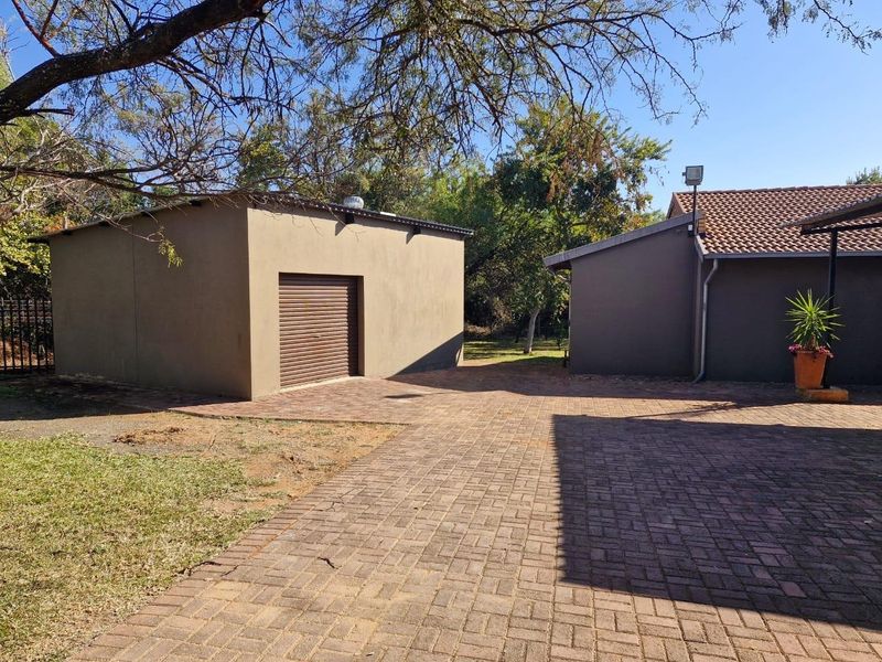 A view of the rear exterior area featuring a paved driveway, a detached garage, and well-maintained building facades.