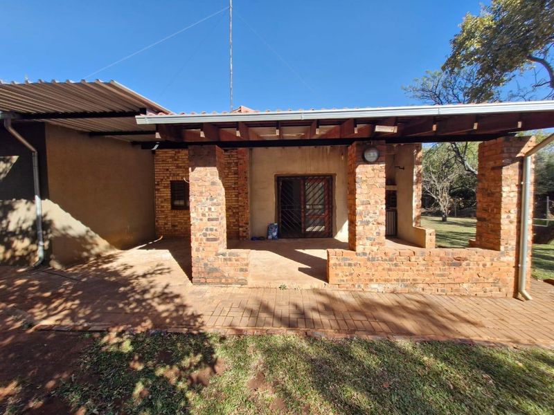 Covered outdoor patio featuring exposed brick pillars, timber roof beams, and brick paving, providing a rustic space for outdoor entertaining.