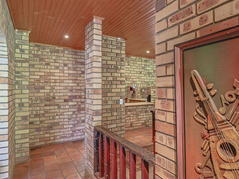 A rustic hallway featuring exposed brickwork, terracotta floor tiles, and a timber-paneled ceiling, leading towards an open-plan living area.