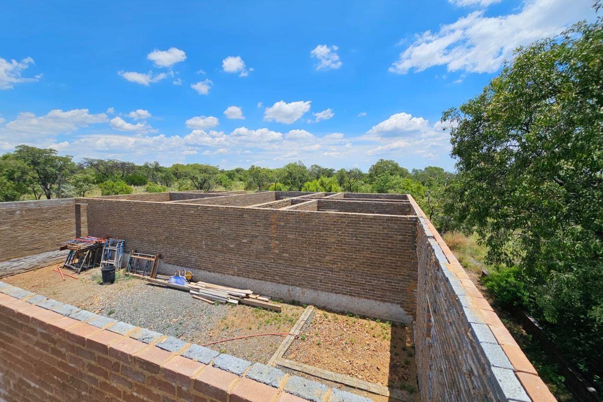 An elevated view of a property under construction, showing the brick masonry walls and structural layout of the building shell.