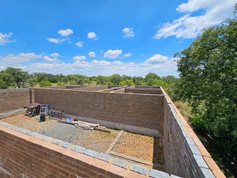 An elevated view of a property under construction, showing the brick masonry walls and structural layout of the building shell.