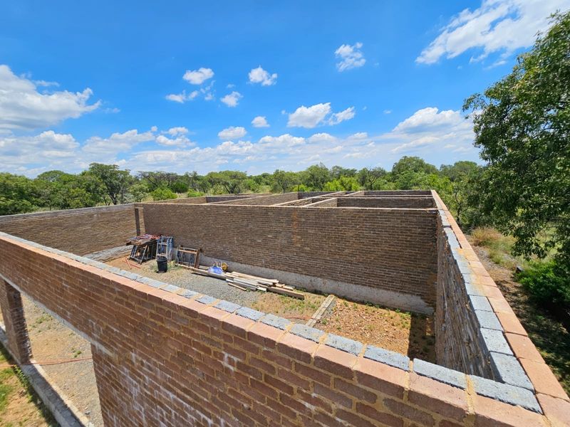 An aerial view of a property under construction, showing the brick masonry walls and foundation layout of the building structure.