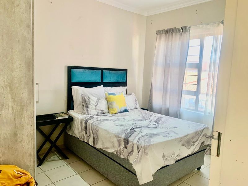 A functional bedroom featuring tiled flooring, a built-in wardrobe, and a window with security bars, offering a neutral space ready for personalization.