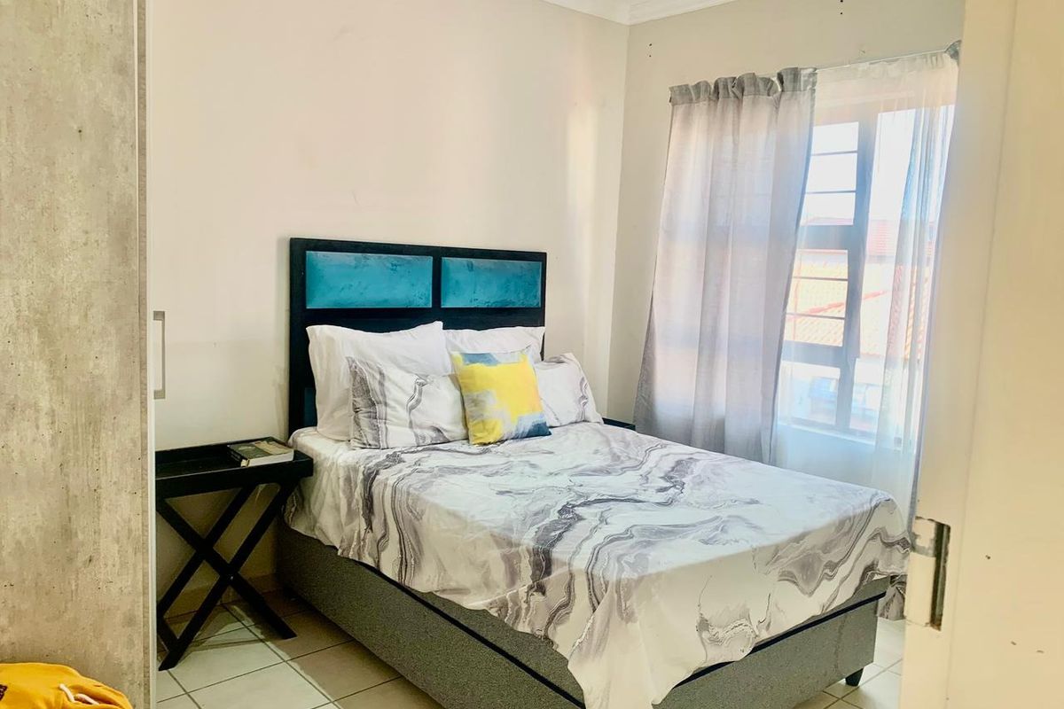 A functional bedroom featuring tiled flooring, a built-in wardrobe, and a window with security bars, offering a neutral space ready for personalization.