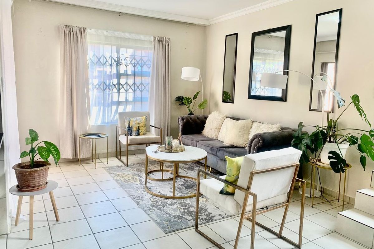 A bright living room featuring tiled flooring, decorative cornicing, and a security gate on the window, offering a neutral base for interior updates.