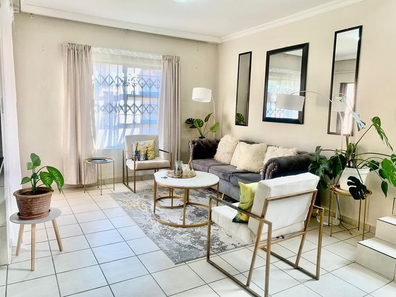 A bright living room featuring tiled flooring, decorative cornicing, and a security gate on the window, offering a neutral base for interior updates.