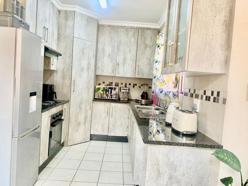 A functional kitchen featuring light wood-grain cabinetry, granite countertops, a stainless steel sink, and built-in oven with extractor fan.