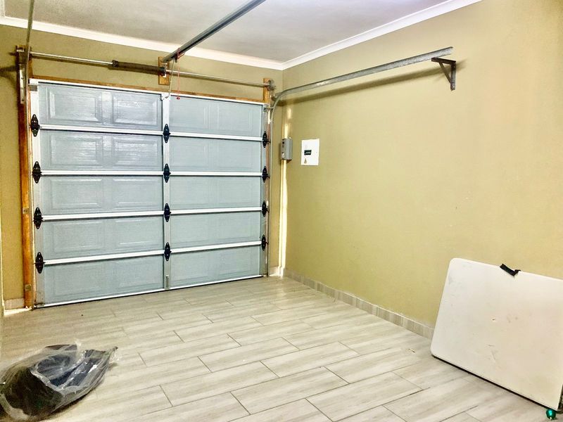 A clean, empty garage space featuring modern tiled flooring and a functional sectional garage door.