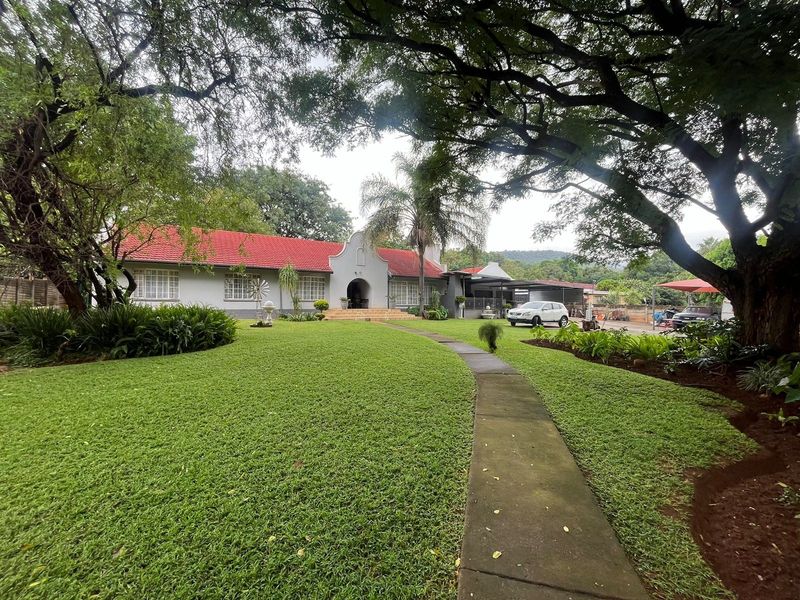 A charming single-story home featuring a classic tiled roof, a welcoming arched entrance, and a well-maintained front garden with a paved walkway.