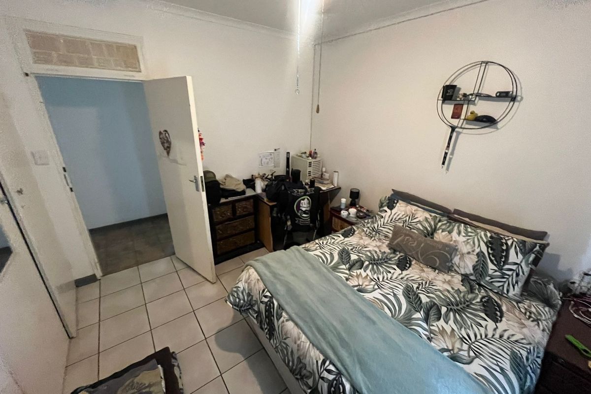 A bedroom featuring tiled flooring, a ceiling fan, and coved cornicing, providing a functional space with potential for cosmetic updates.