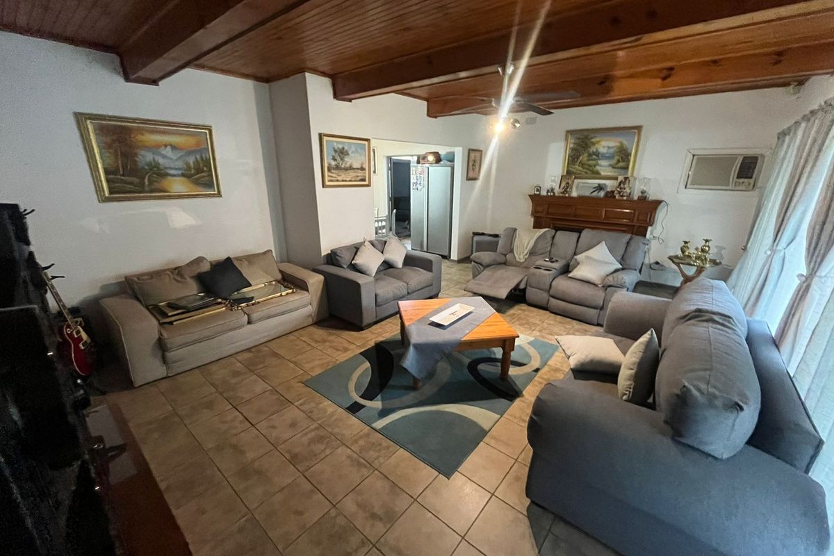 Spacious living room featuring exposed timber beam ceilings, ceramic tiled flooring, and a traditional wooden fireplace mantel.