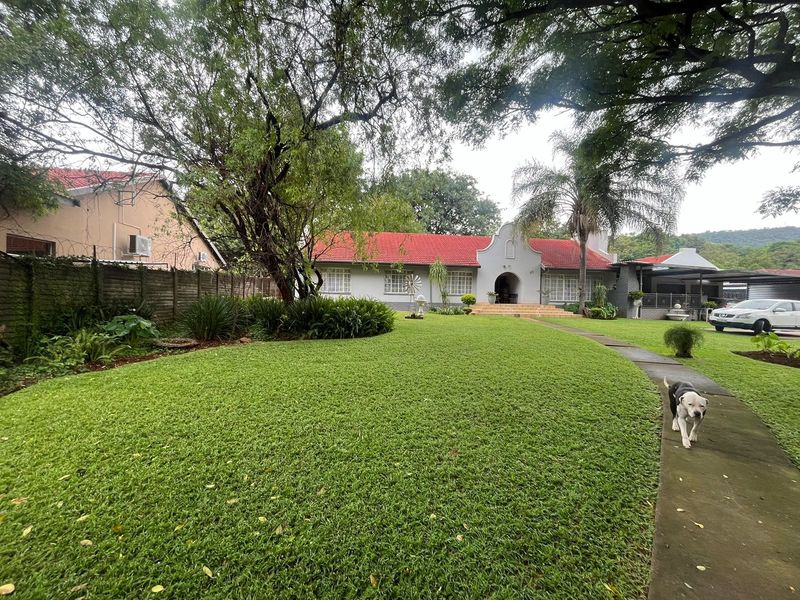 A well-maintained single-story house featuring a classic gabled facade, a red tiled roof, and a spacious front garden with a paved walkway.