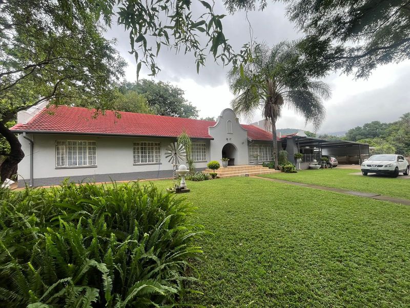 A well-maintained single-story residence featuring a classic tiled roof, a spacious front lawn, and an attached carport with a paved driveway.