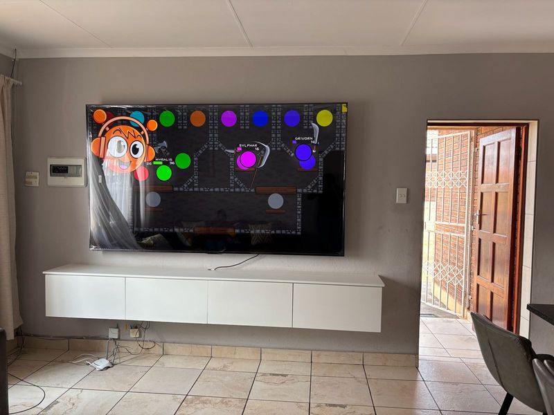 Living room featuring ceramic floor tiles, a wall-mounted media console, and direct access to an exterior area through a security gate and timber door.