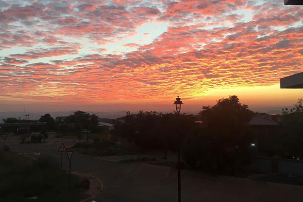A scenic sunset view overlooking a residential street and surrounding landscape.