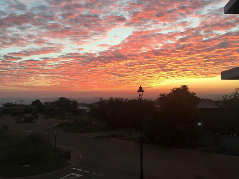 A scenic sunset view overlooking a residential street and surrounding landscape.