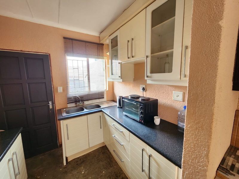 Compact kitchen featuring built-in cabinetry, laminate countertops, and a double sink, offering functional storage and preparation space.