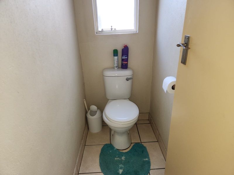 A compact guest toilet featuring tiled flooring and a standard white toilet suite.