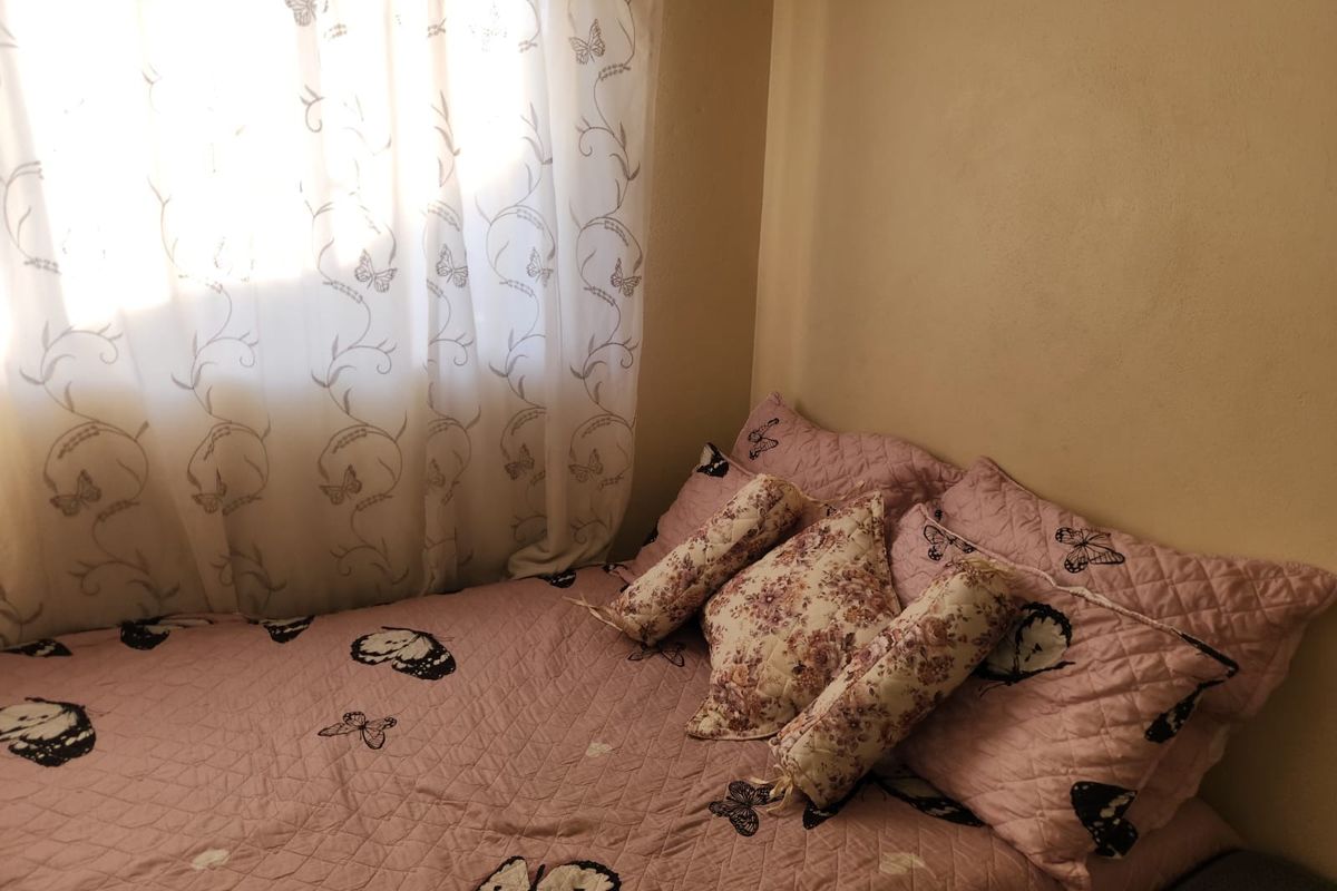 A compact bedroom featuring a window with curtains, providing natural light to the space.