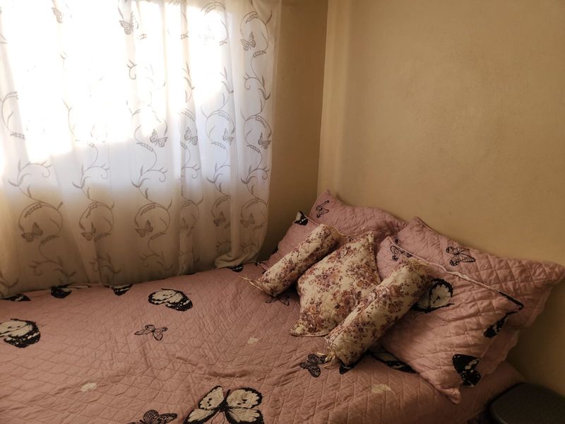 A compact bedroom featuring a window with curtains, providing natural light to the space.