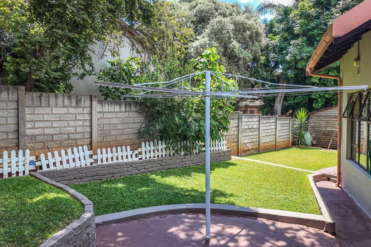 A private rear garden featuring a paved patio, lawn, and secure concrete block boundary walls, providing a functional outdoor space.