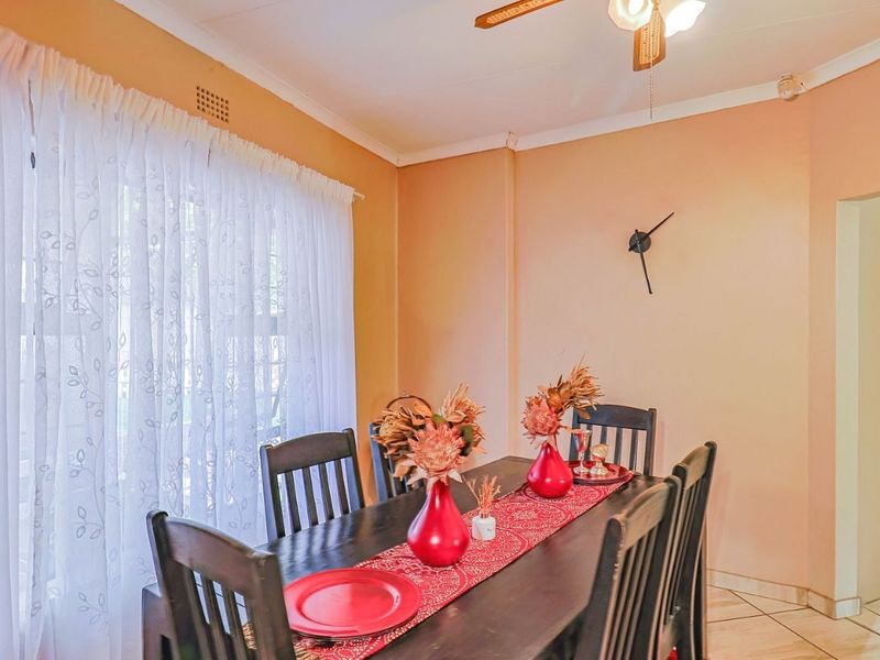 A dining room featuring tiled flooring, ceiling fan, and neutral wall finishes, providing a functional space for family meals.