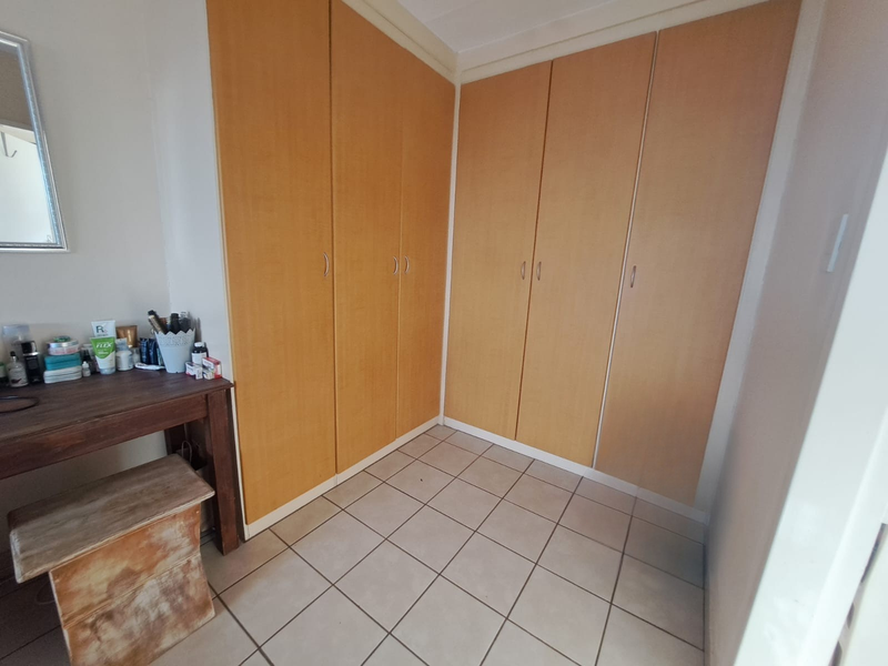 Bedroom featuring light wood-finish built-in cupboards and neutral tiled flooring, providing ample storage space.