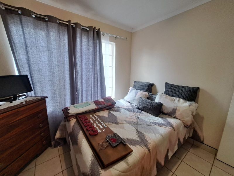 A functional bedroom featuring tiled flooring and neutral wall finishes, providing a comfortable space with natural light from the window.