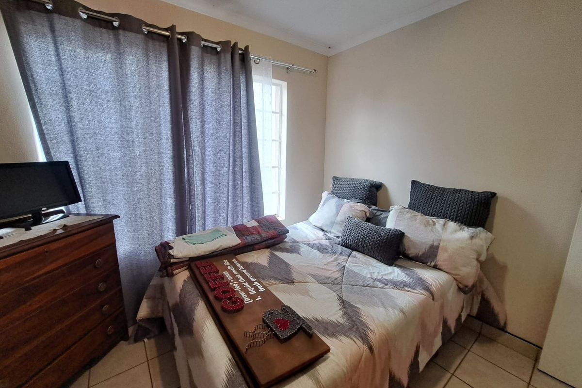 A functional bedroom featuring tiled flooring and neutral wall finishes, providing a comfortable space with natural light from the window.