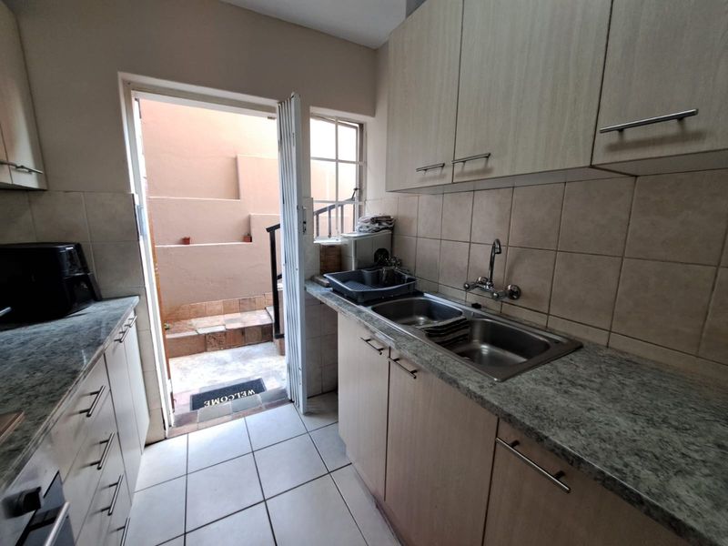 Functional scullery featuring laminate cabinetry, double bowl sink, and direct access to a small rear courtyard area.