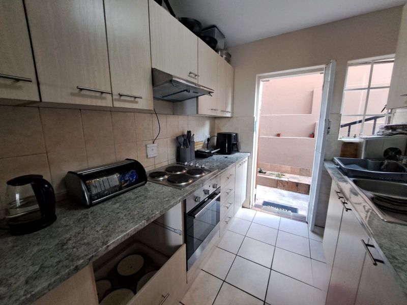 Functional kitchen featuring laminate cabinetry, built-in oven and hob, tiled backsplash, and direct access to an outdoor courtyard area.