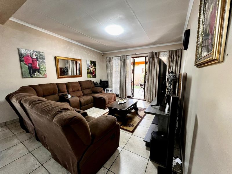 A comfortable living room featuring tiled flooring and a sliding glass door that provides access to the outdoor patio area.
