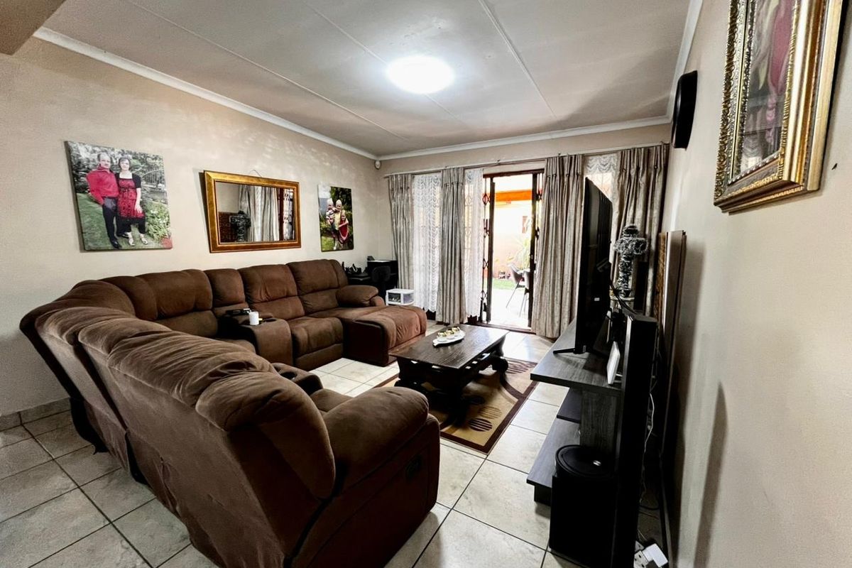 A comfortable living room featuring tiled flooring and a sliding glass door that provides access to the outdoor patio area.