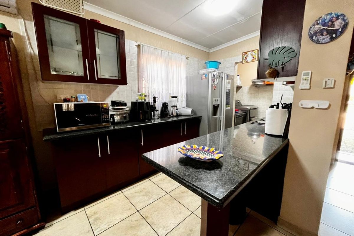 A functional kitchen featuring dark wood cabinetry, granite countertops, a breakfast bar, and tiled flooring, offering a practical layout for daily meal preparation.