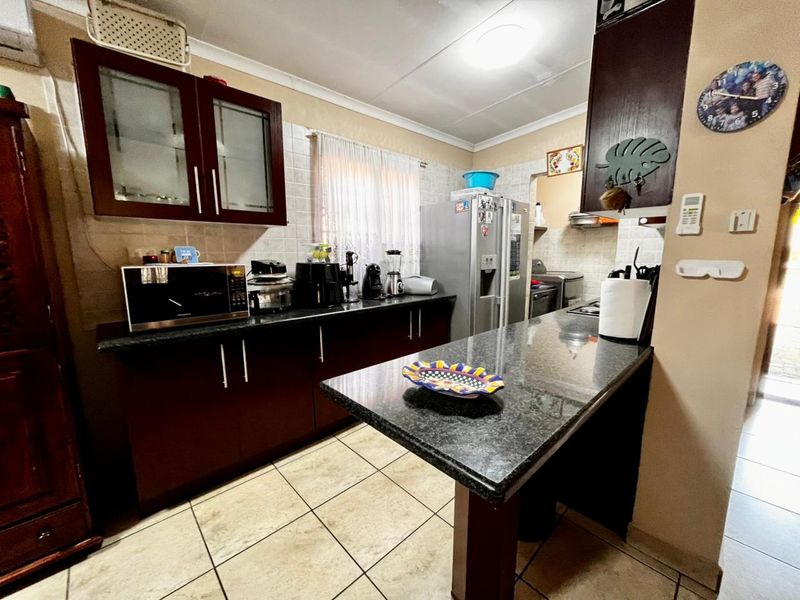 A functional kitchen featuring dark wood cabinetry, granite countertops, a breakfast bar, and tiled flooring, offering a practical layout for daily meal preparation.