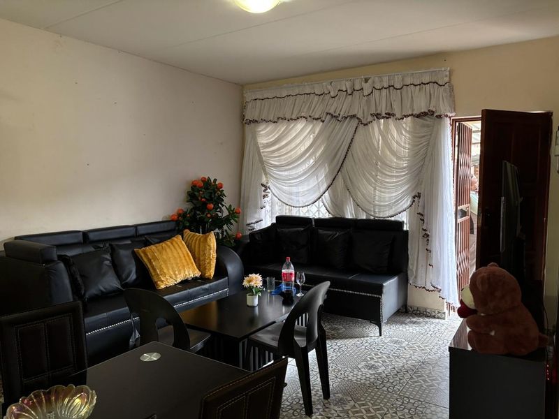 A living room area featuring patterned floor tiles and access to an exterior security gate.
