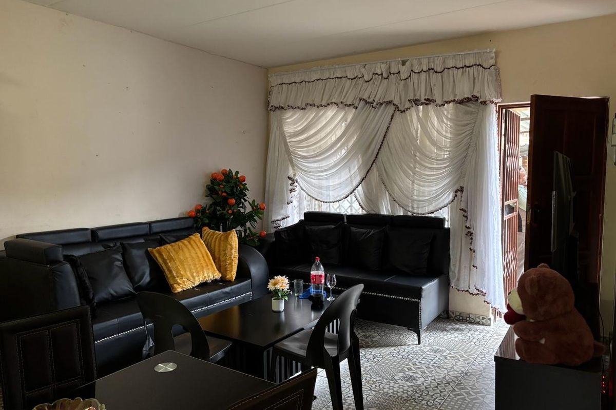 A living room area featuring patterned floor tiles and access to an exterior security gate.