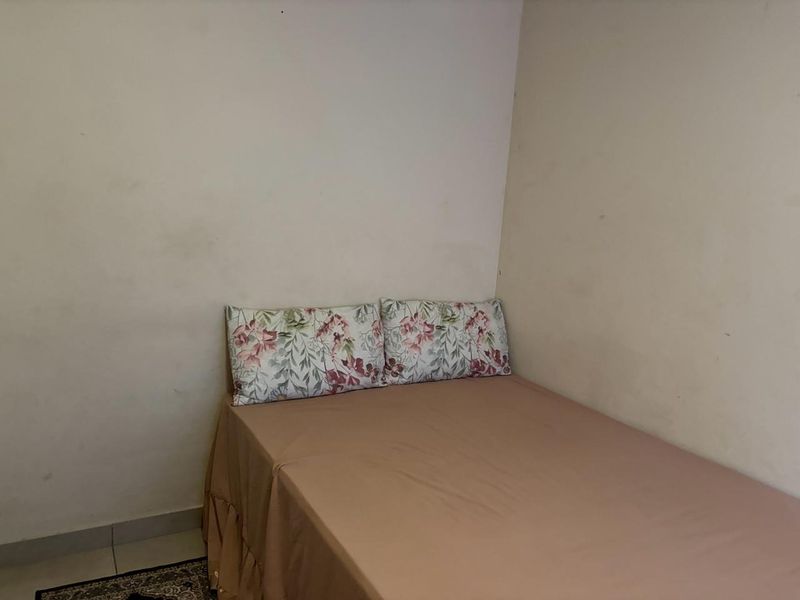 A compact bedroom space featuring plain walls in need of maintenance and a simple layout.