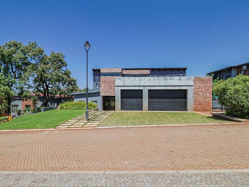 Modern double-story house featuring a contemporary brick and concrete facade with a double garage and well-maintained front lawn.